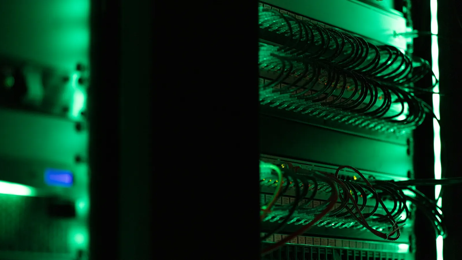 Server racks and network cables lit green in a data center