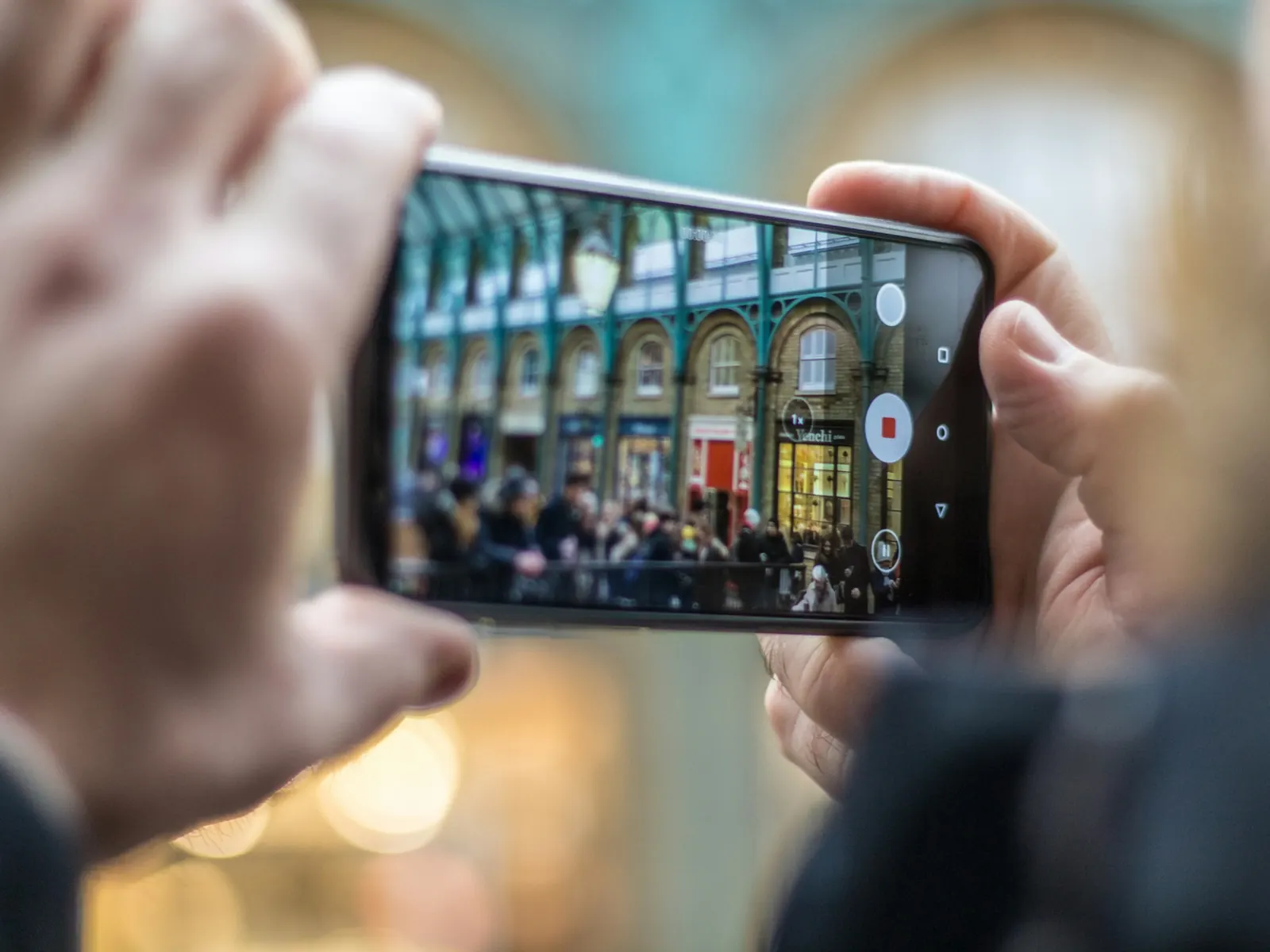 Creator filming a busy market hall with a smartphone